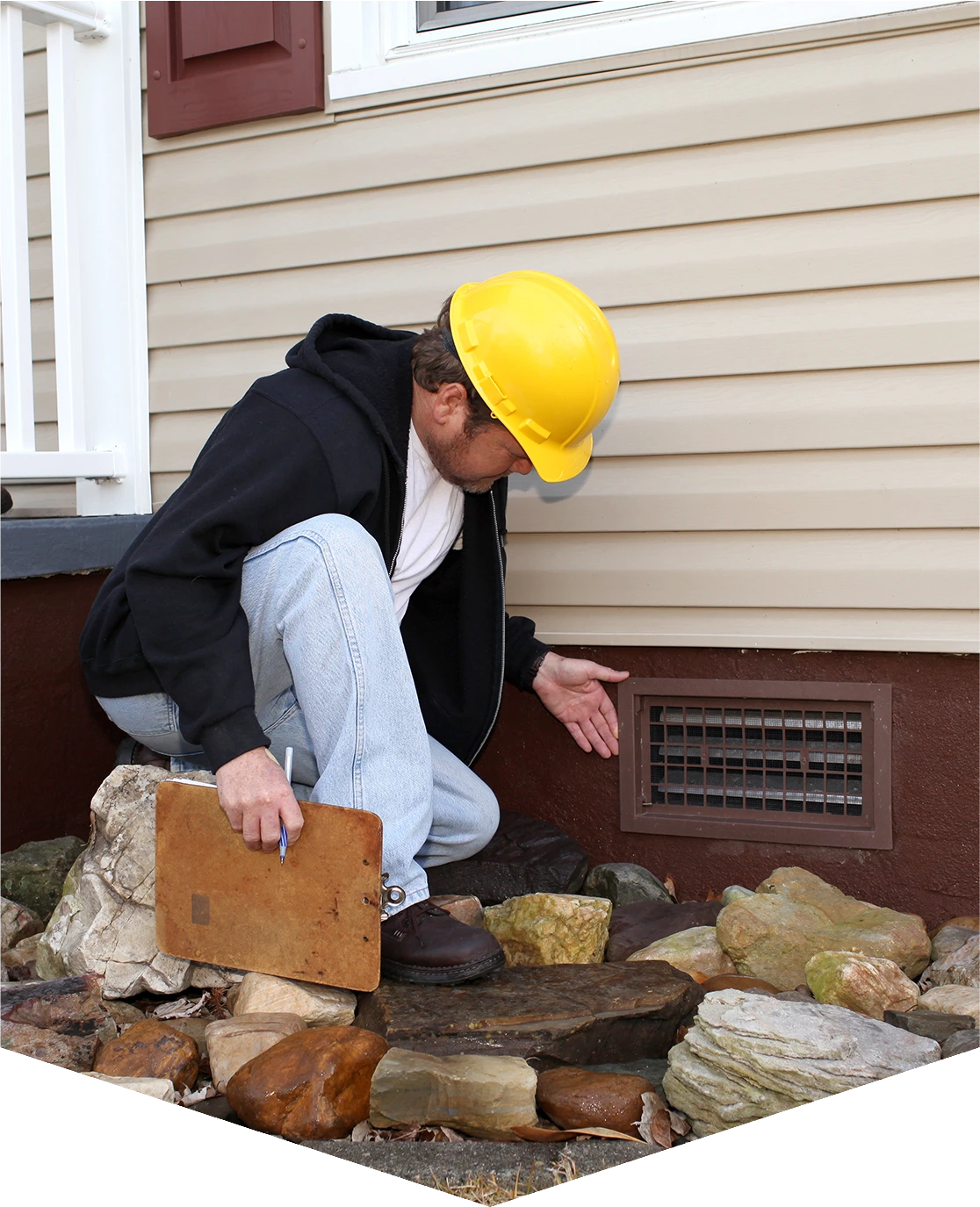 Inspector examining house foundation vent area.