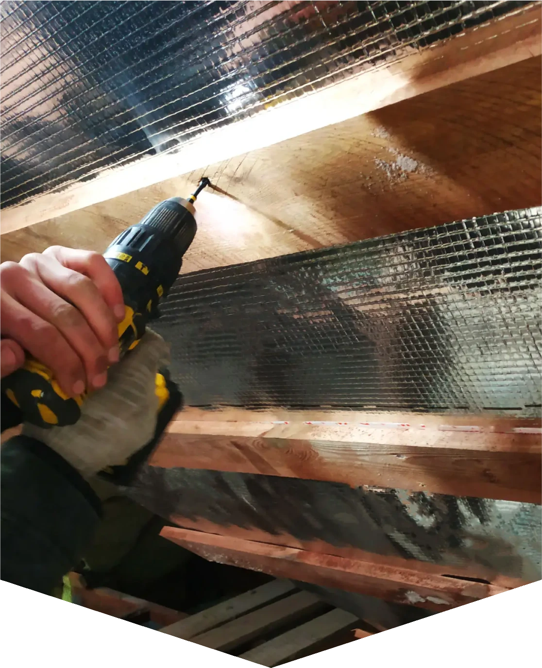 Person using drill on wooden beams.