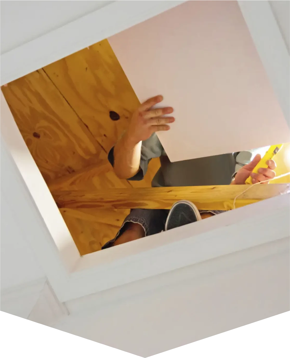 Person working on ceiling through attic opening.