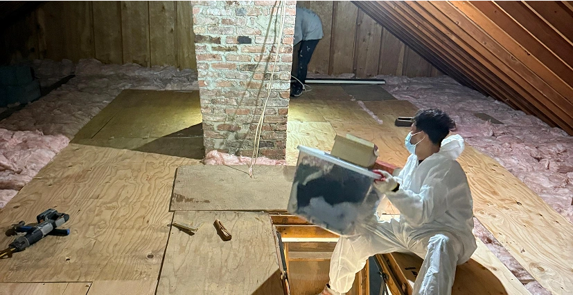 Person working in attic insulation installation.