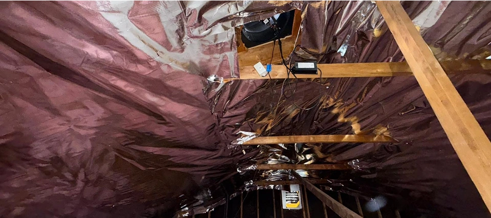 Insulated attic with wooden beams and wires.