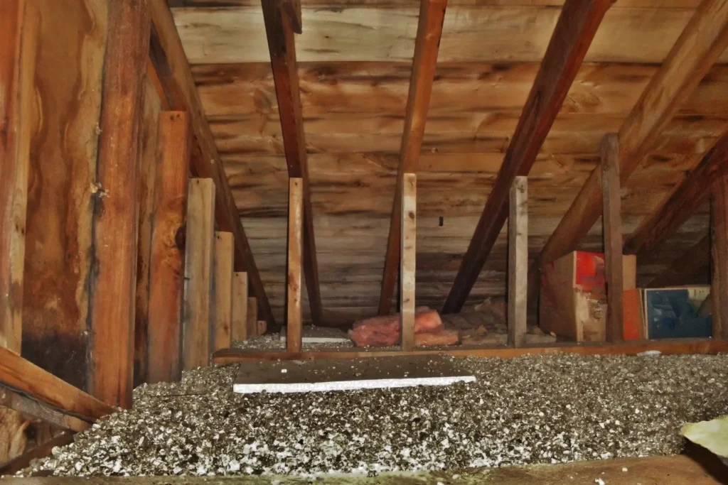 Attic with exposed beams and scattered debris.