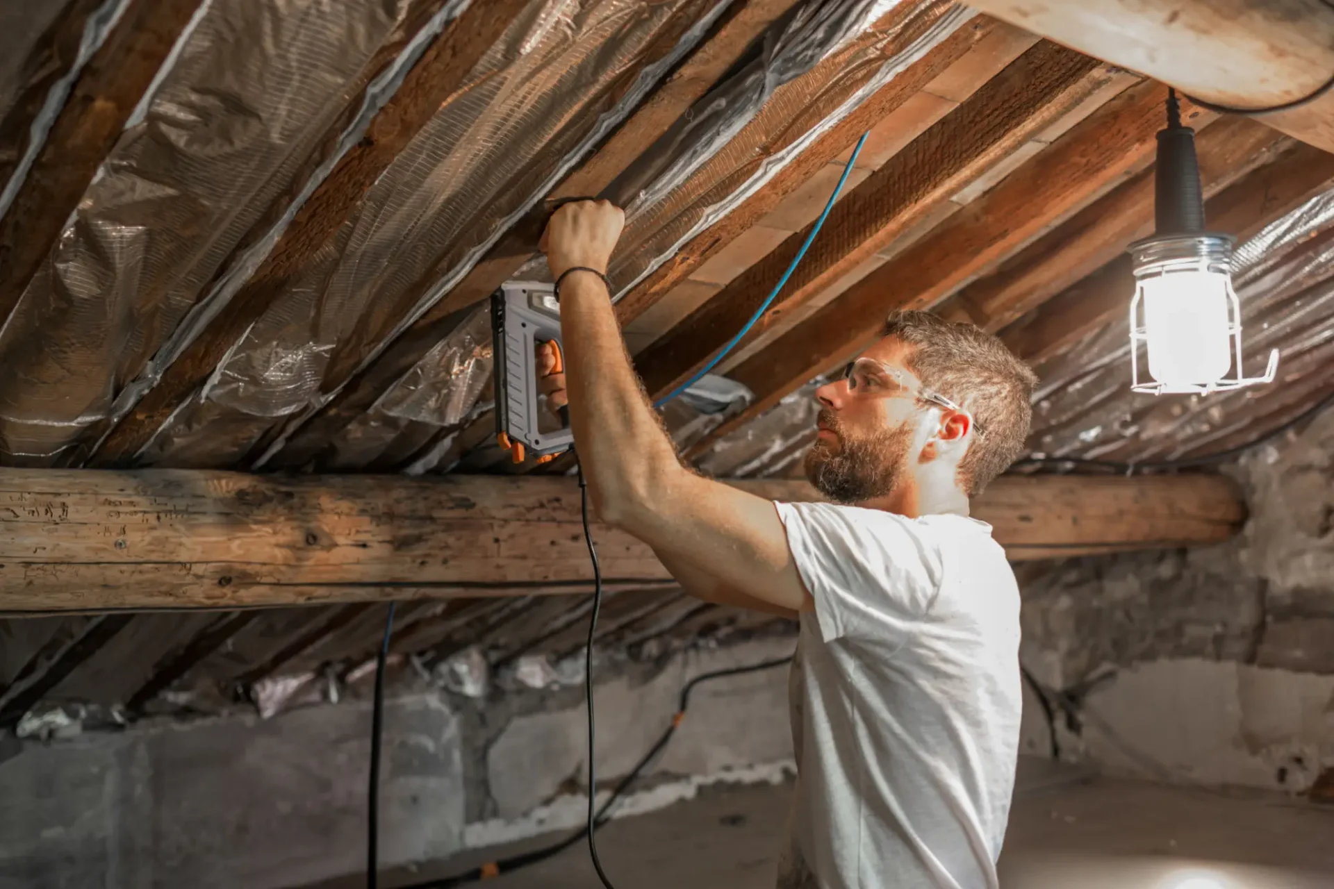 Man installing insulation in attic ceiling.