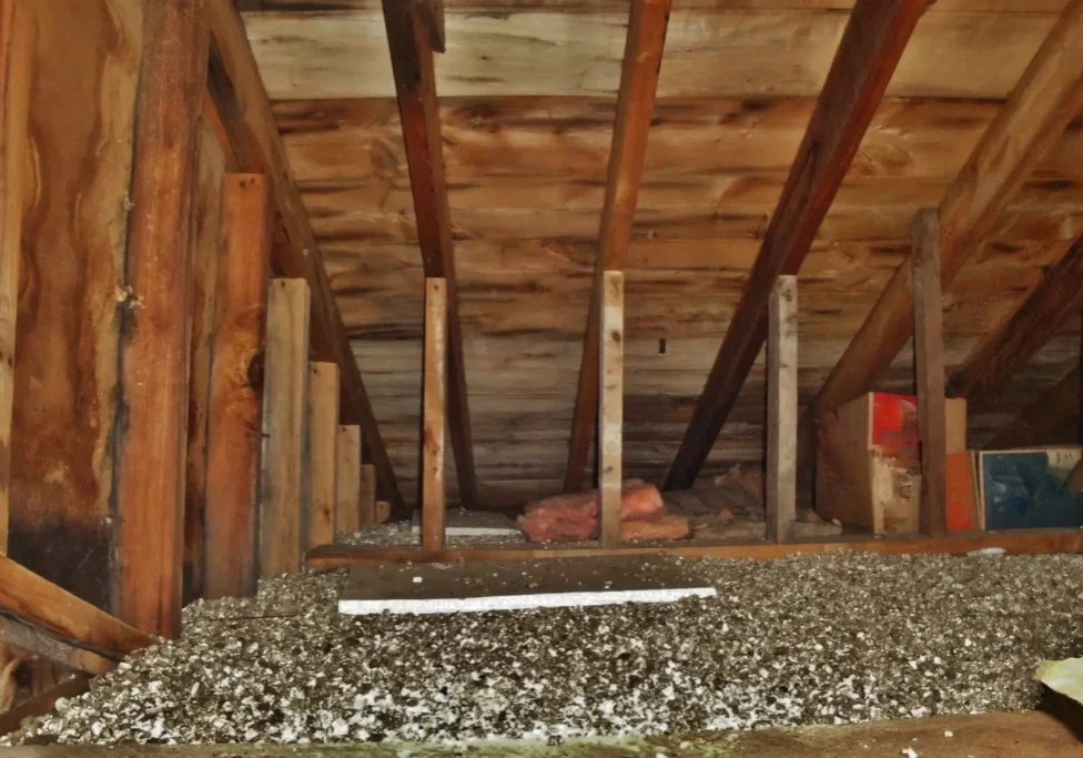 Attic with exposed beams and scattered debris.