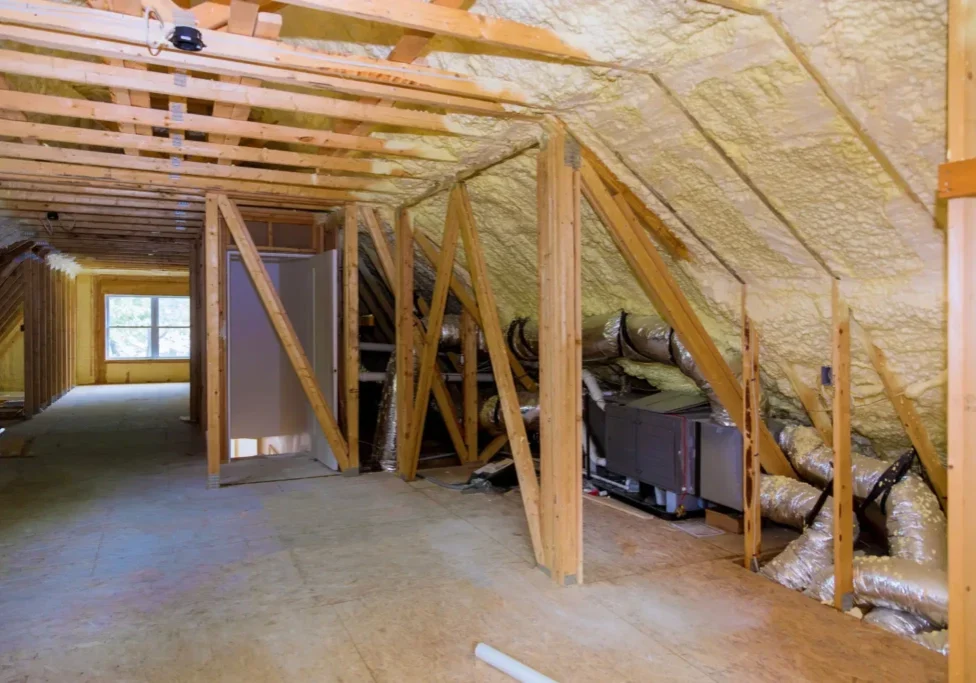 Unfinished attic with insulation and ductwork.
